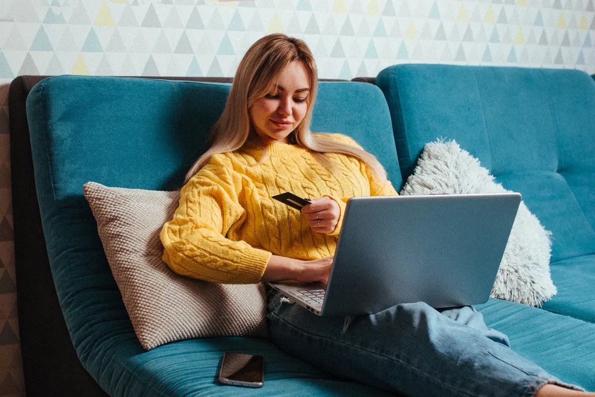 Cliente faisant un achat en ligne sur son ordinateur portable, carte bancaire à la main : l’instant du panier abandonné