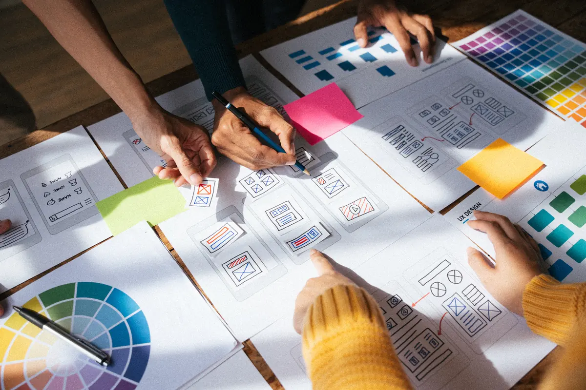 Équipe disposant des maquettes d’écrans et des nuanciers sur une table : conception UX avant la création d’un site web