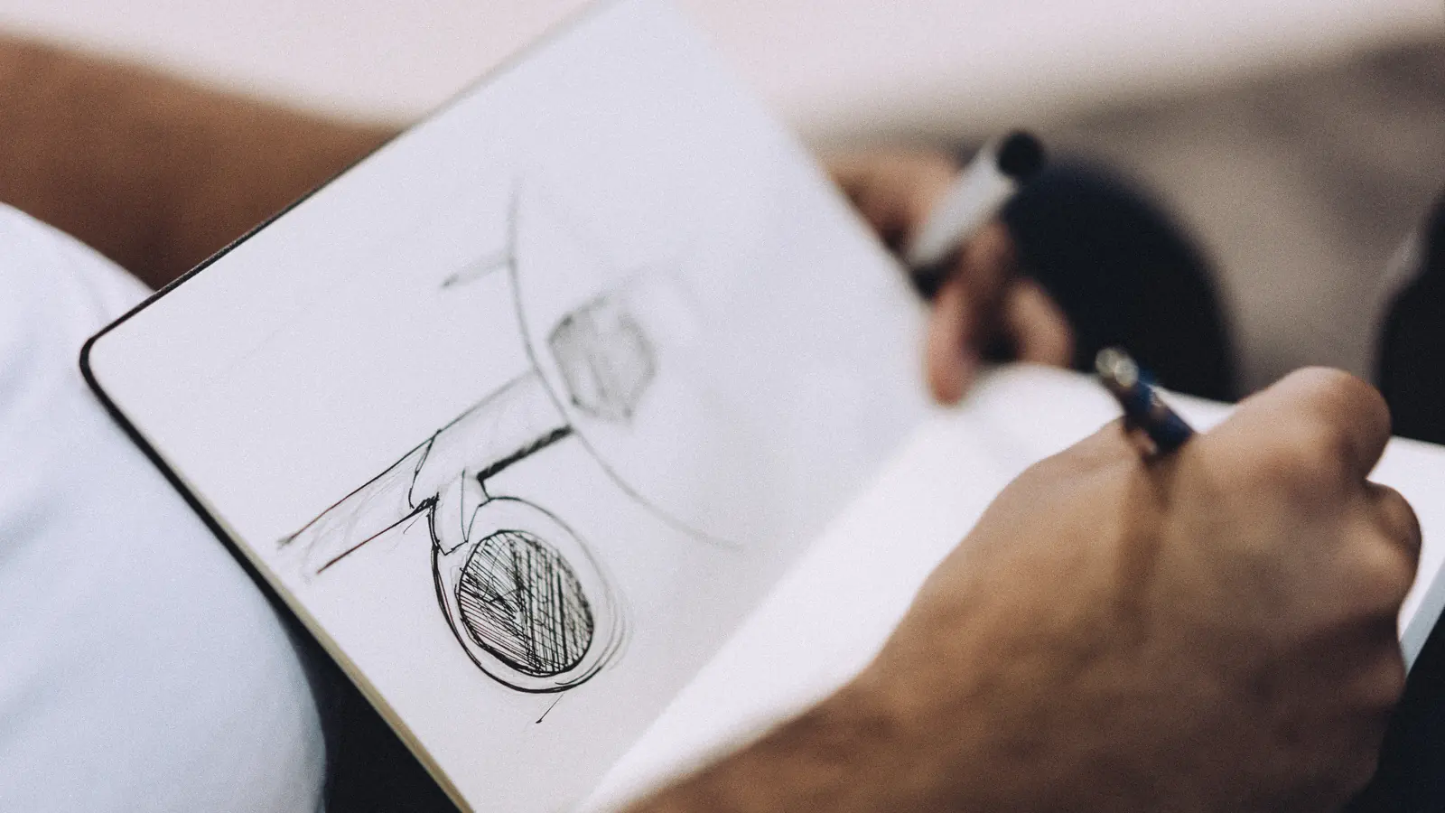 Main d’un graphiste esquissant un logo au feutre dans un carnet : prix d’un logo professionnel