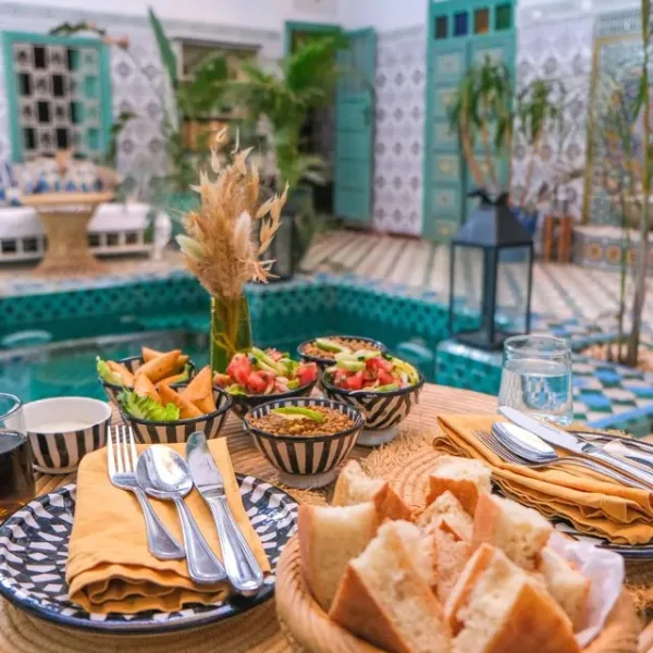 Moroccan dishes set on a table in a riad courtyard
