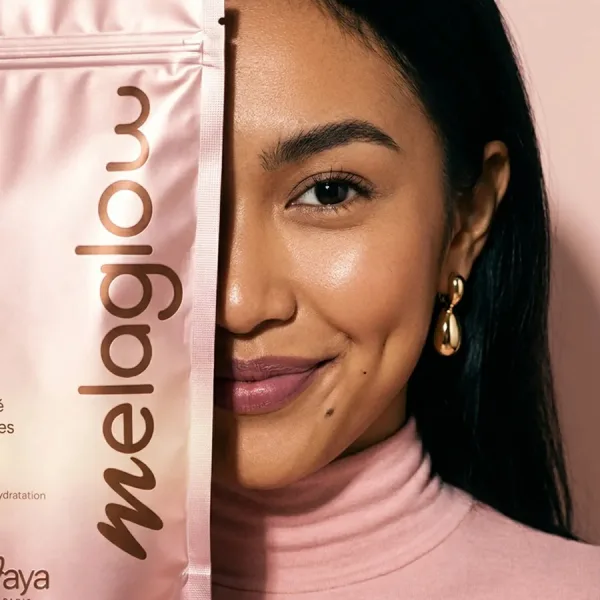 Femme tenant le sachet MelaGlow, complément alimentaire pour peaux riches en mélanine