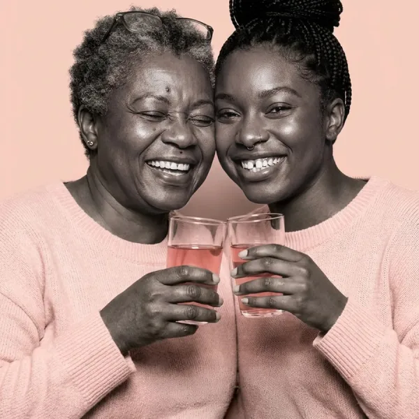 Grand-mère et petite-fille à la peau noire trinquant avec leur verre de MelaGlow