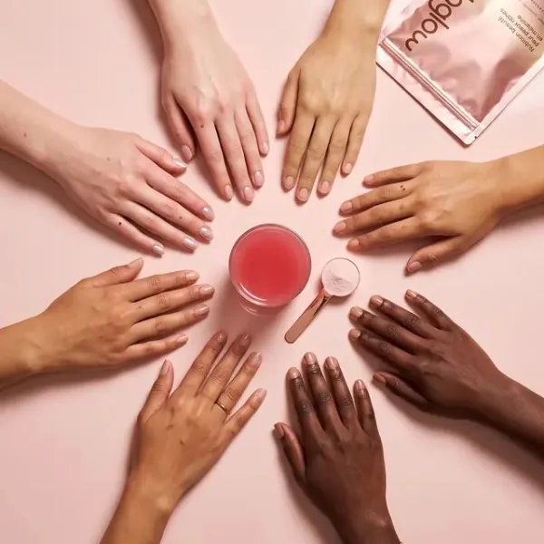 Mains de toutes les carnations autour d’un verre de MelaGlow et de son sachet