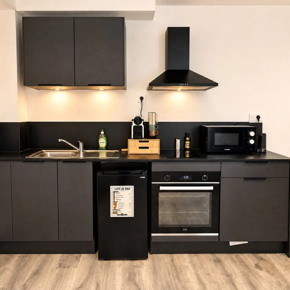A black fitted kitchen with an oven, a microwave and a fridge