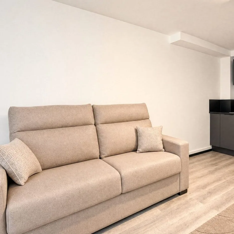 The duplex living room: a beige sofa bed and a black kitchen
