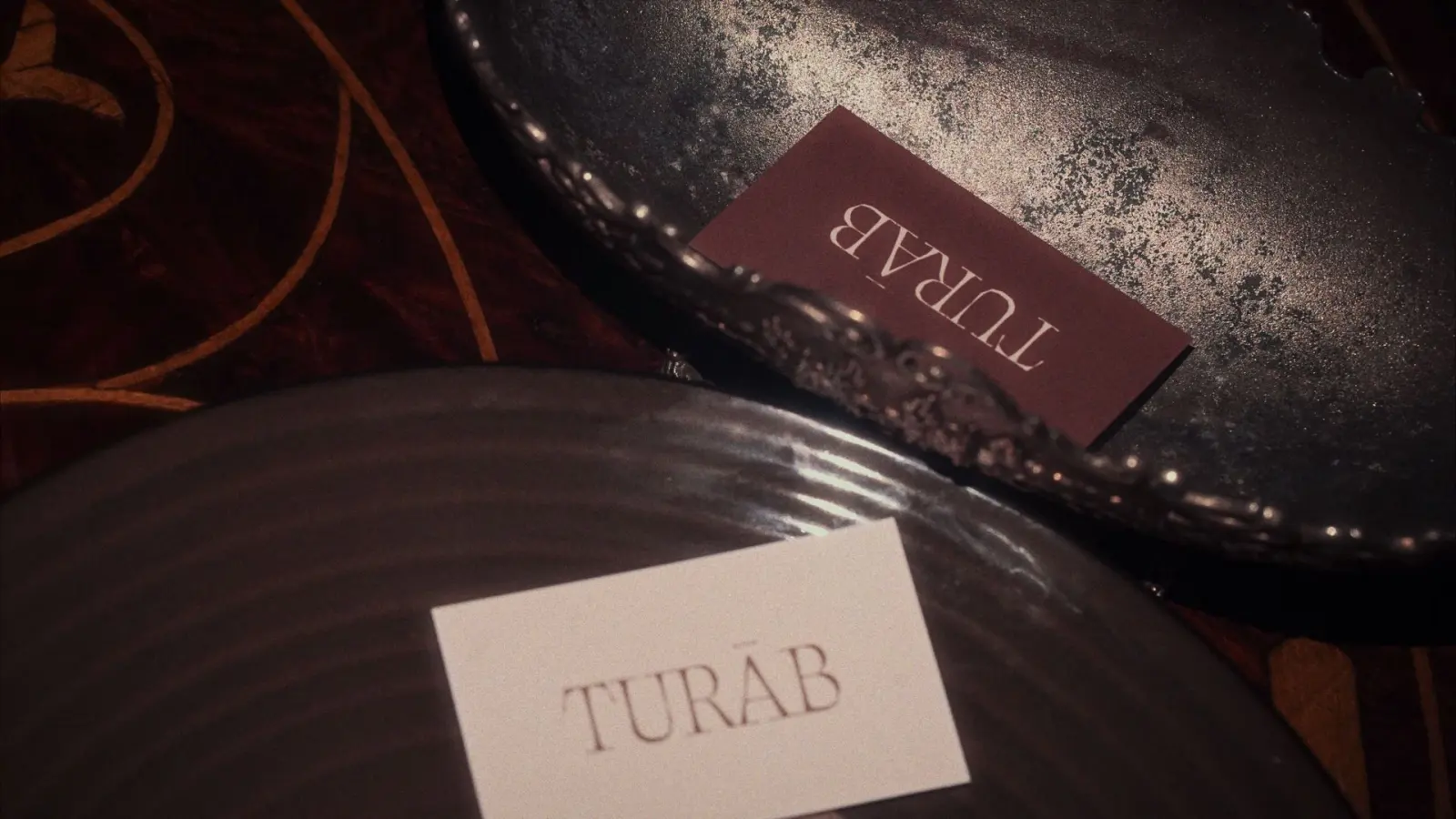 Turāb business cards on an antique metal tray and a stoneware plate