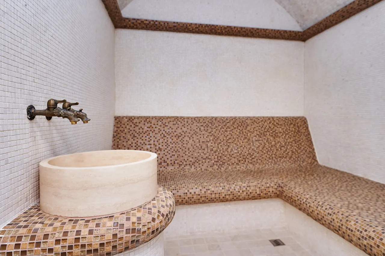 A hammam with a mosaic bench and a stone basin