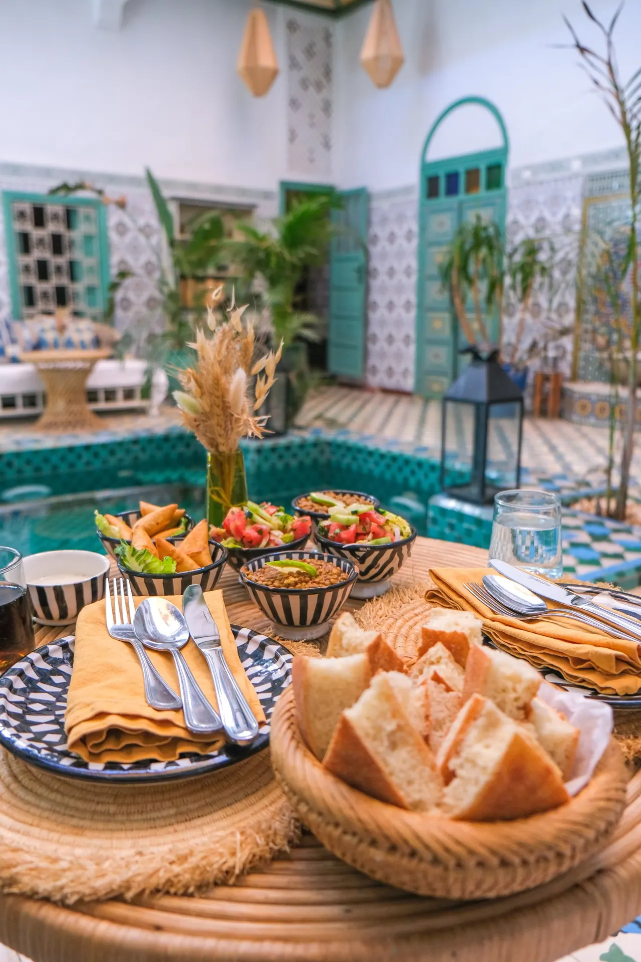 Moroccan dishes set on a table in a riad courtyard