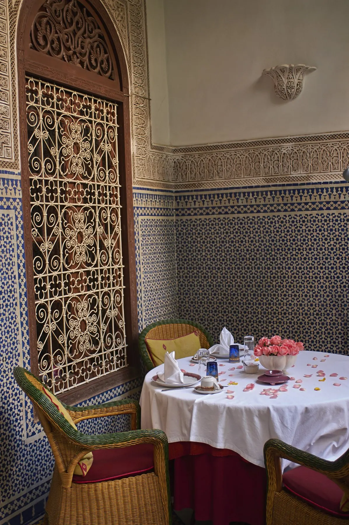 A table set in a room with carved wooden screens and tiled walls