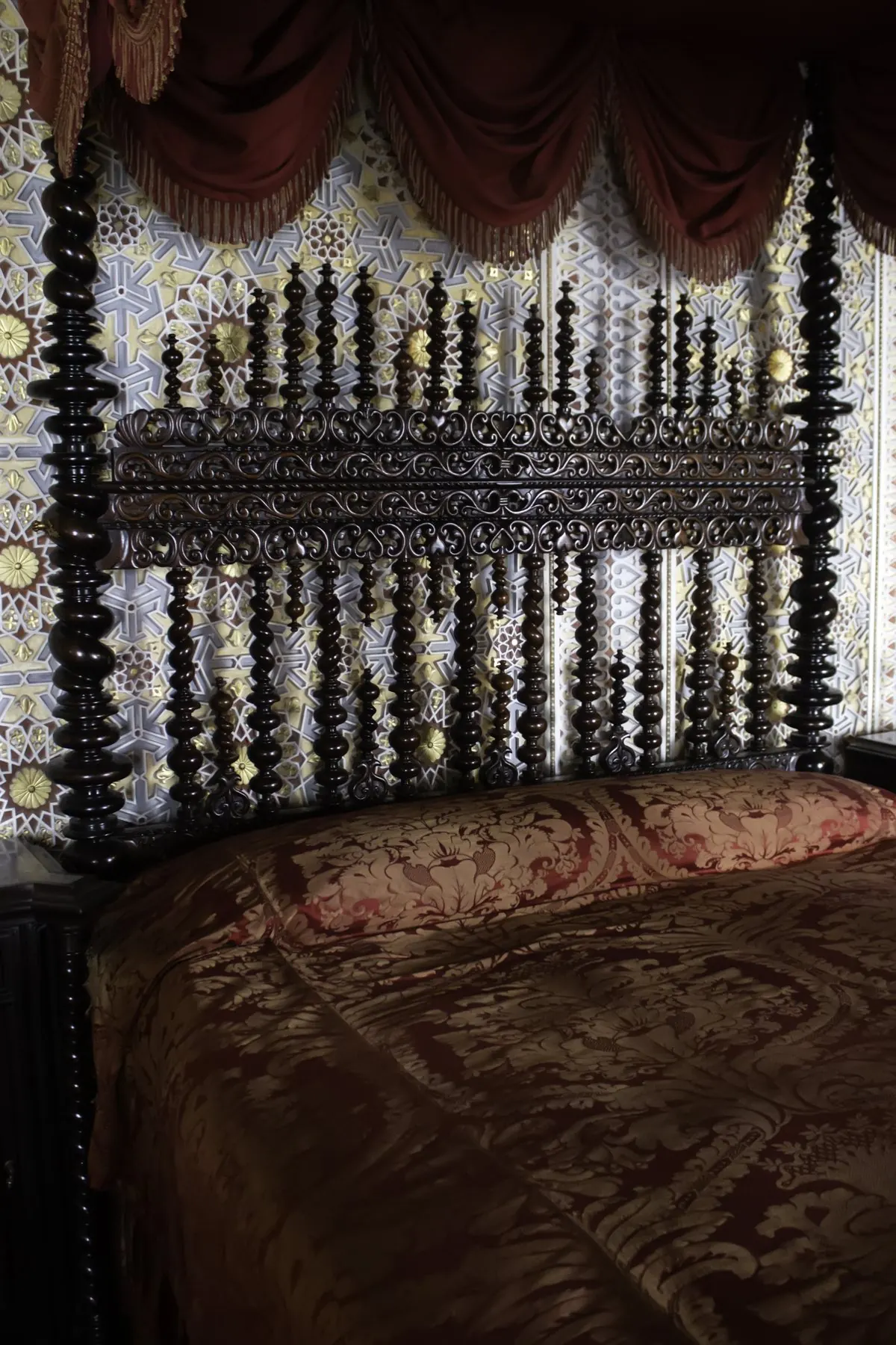 A dark turned-wood bed under a draped canopy