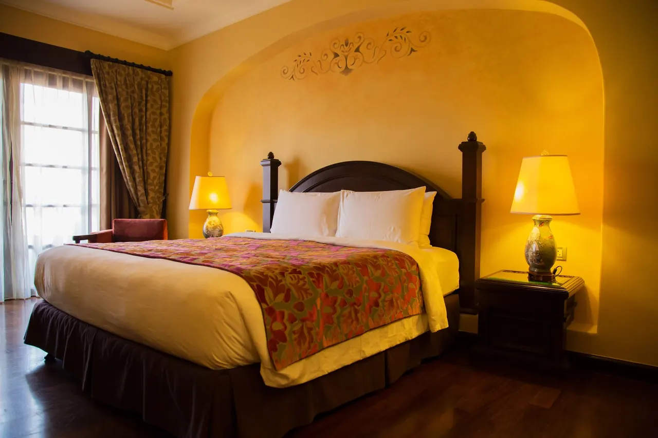 Bedroom with warm yellow walls, a patterned bedspread and two lamps