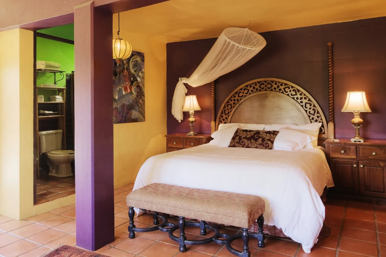 Bedroom with a canopy over the bed, a carved headboard and a terracotta floor