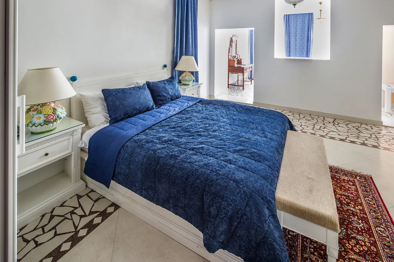Bedroom with a blue quilted bedspread and white walls