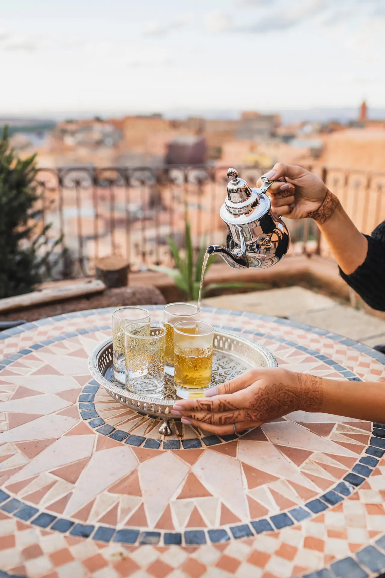Mint tea poured into glasses, with the city in the distance